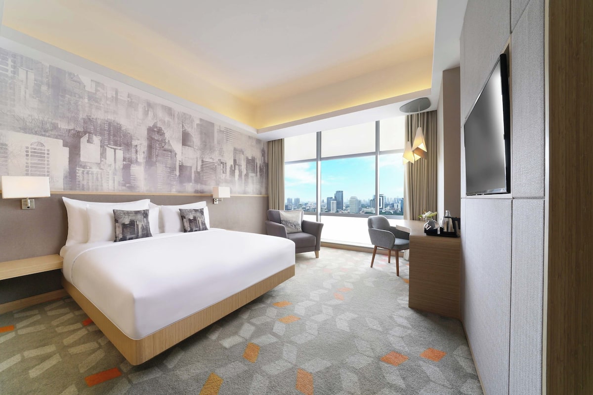 Une chambre d’hôtel avec un grand lit, un bureau, une chaise et un téléviseur.