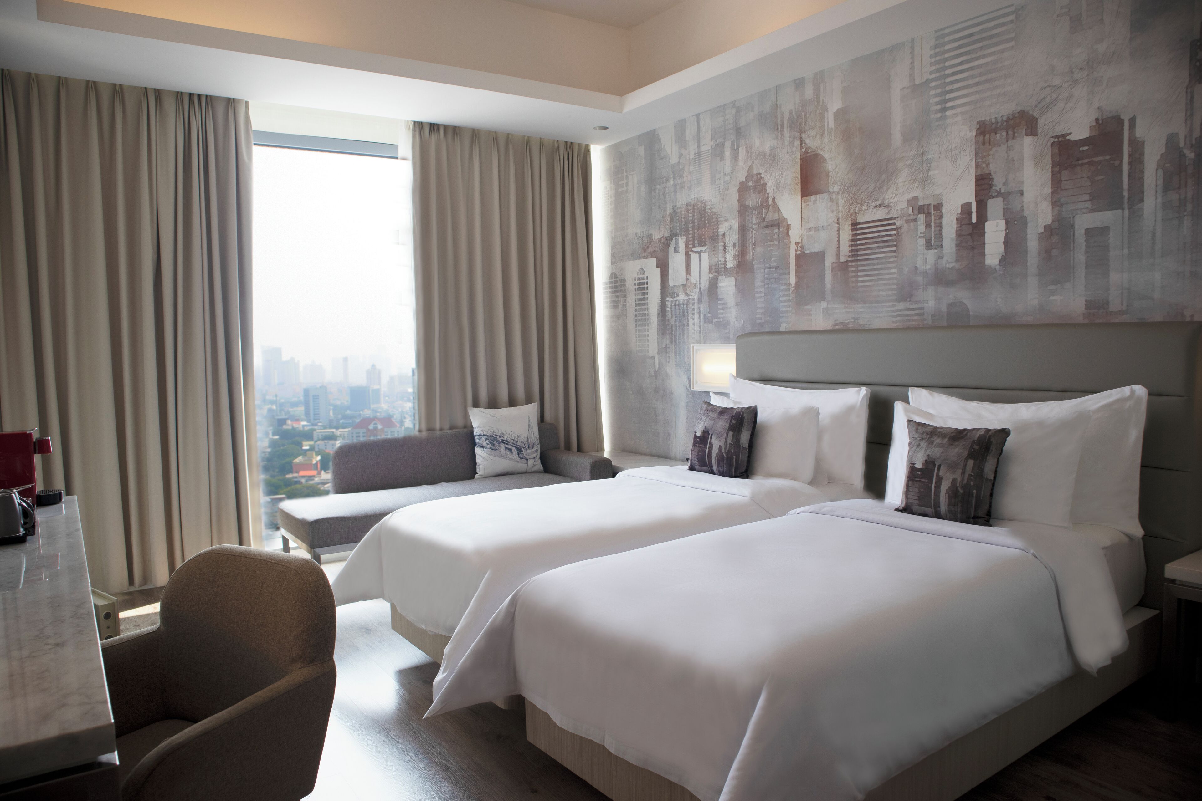 Habitación de hotel con dos camas, un sofá, un escritorio y un ventanal con cortinas.