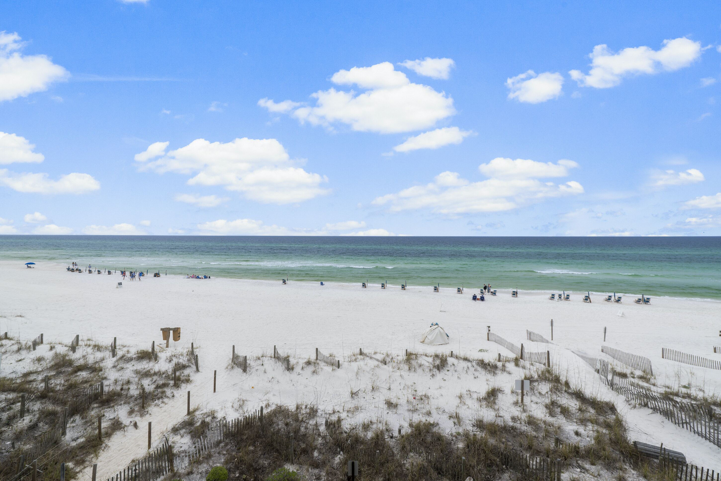 A beach with a sandy shore, a clear sky, and a calm sea.