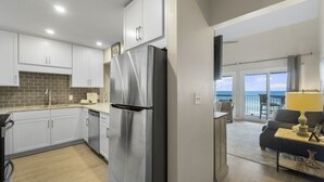 A modern kitchen with stainless steel appliances, white cabinetry, and a view to the outside. - Eastern Shores on 30A by Panhandle Getaways (Santa Rosa Beach)