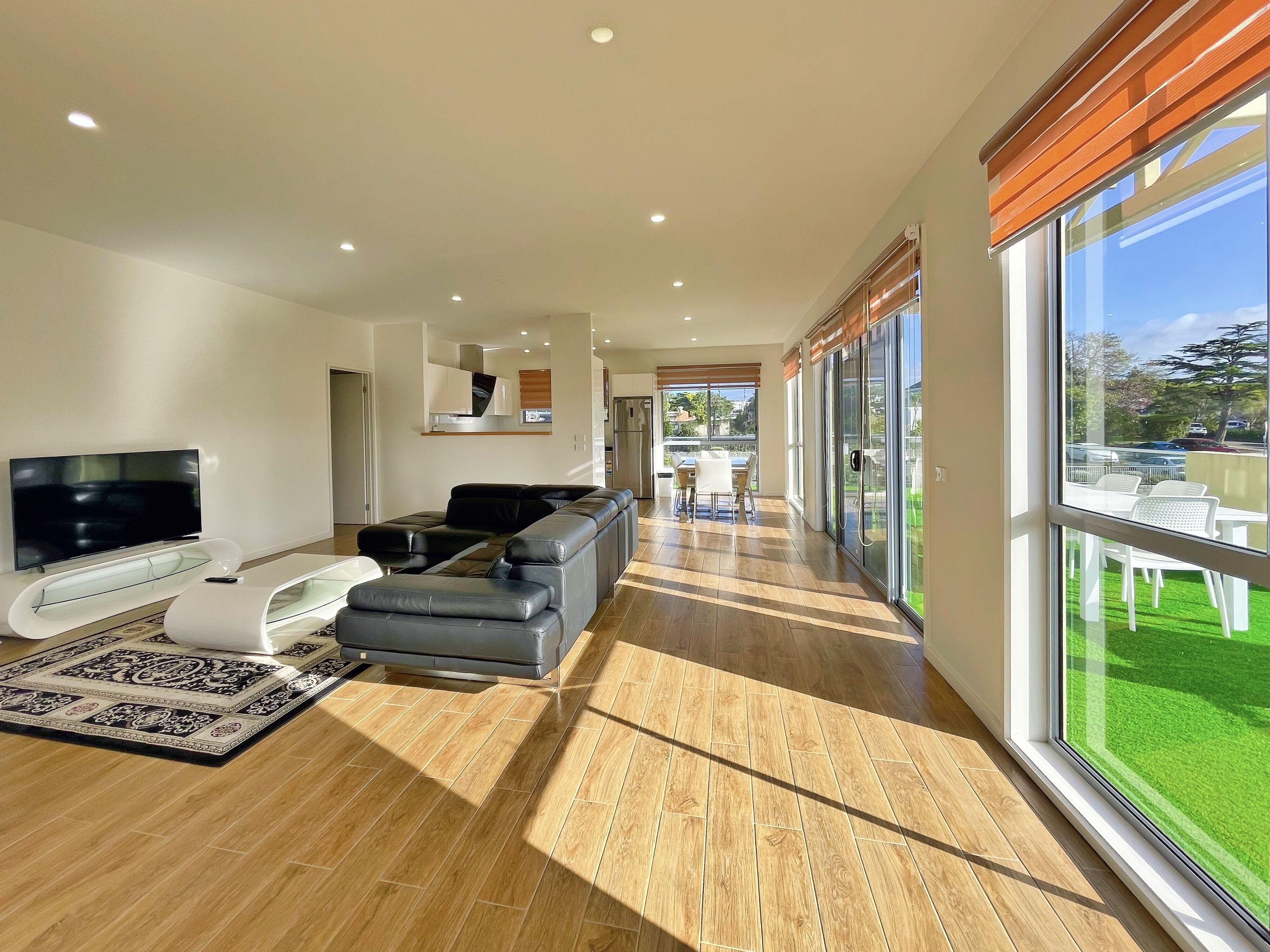 A modern living room with a sectional sofa, a flat-screen TV, and a dining area with a table and chairs.