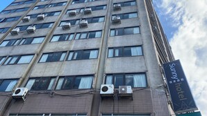 A tall building with multiple air conditioning units and a sign for Sunny Hotel. - Sunny Hotel (Taipei)