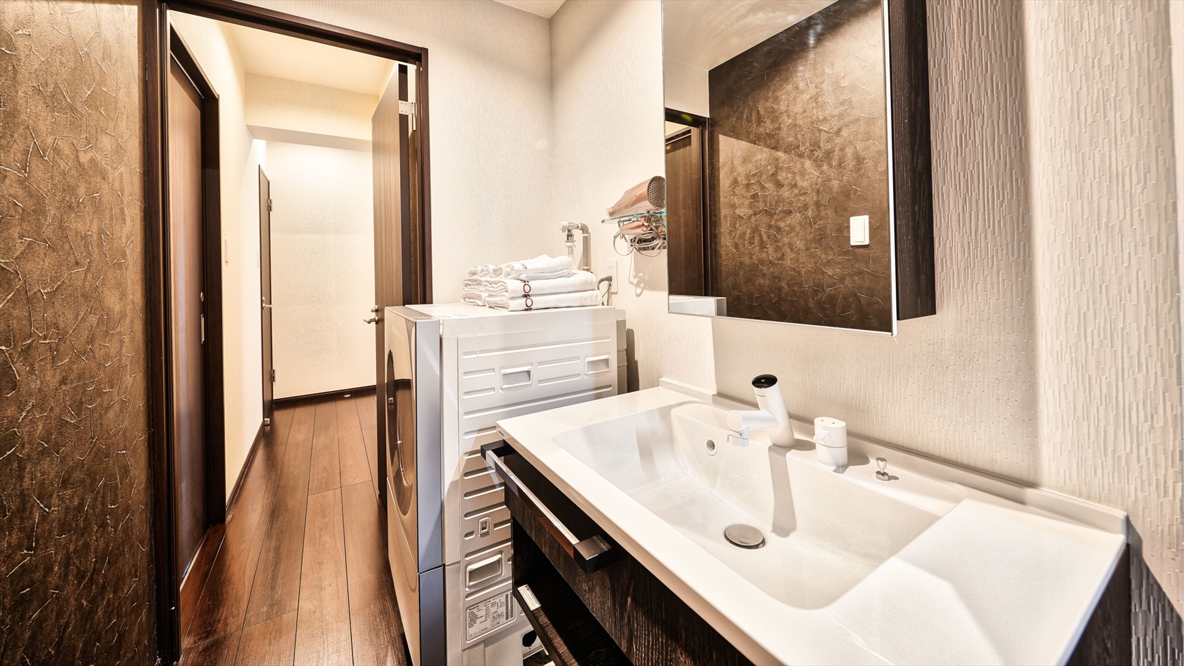 A modern bathroom with a large sink, a mirror, and a towel rack.