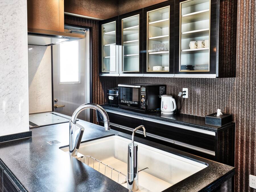 A modern kitchen with a stainless steel sink, a microwave, and a coffee maker.