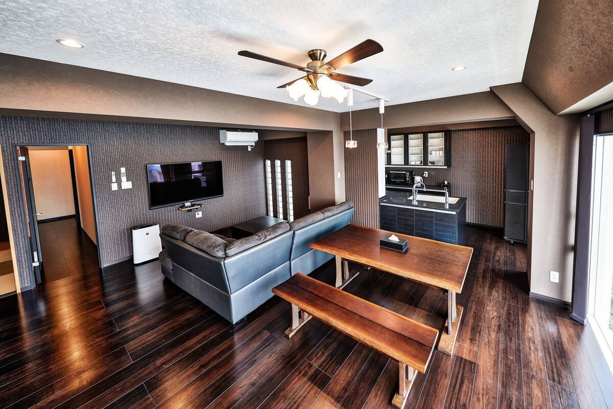 Un salon moderne équipé d’un téléviseur à écran plat, d’un canapé, d’une table à manger et d’un ventilateur de plafond.
