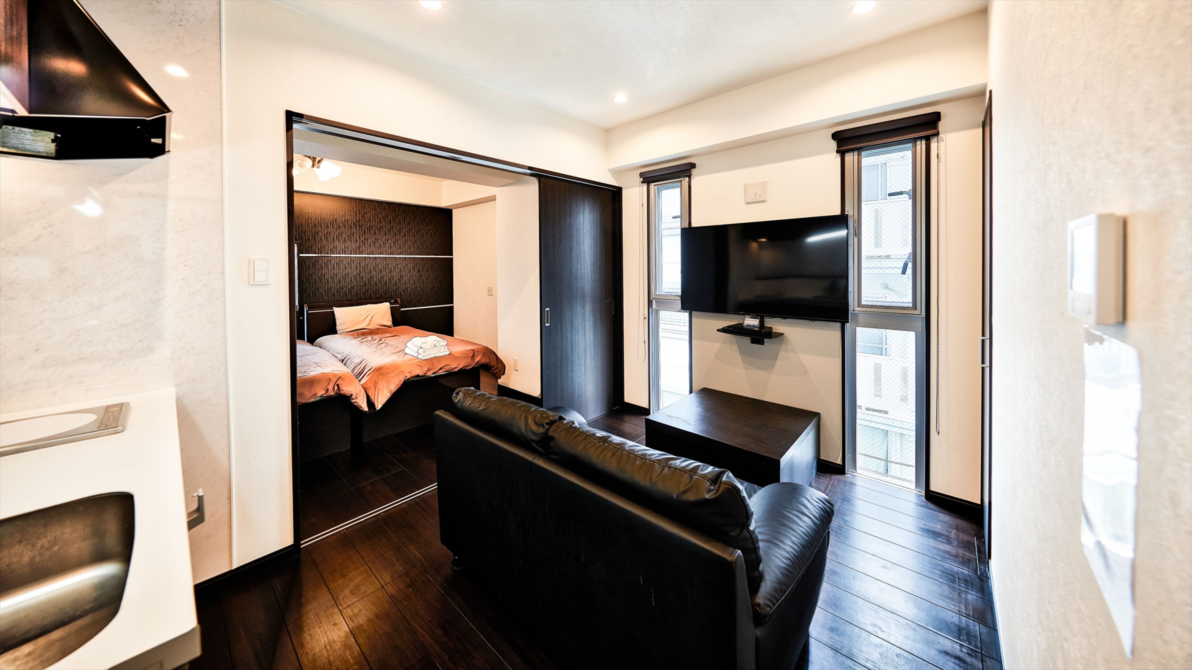 A compact room with a bed, a sofa, a TV, and a small table.