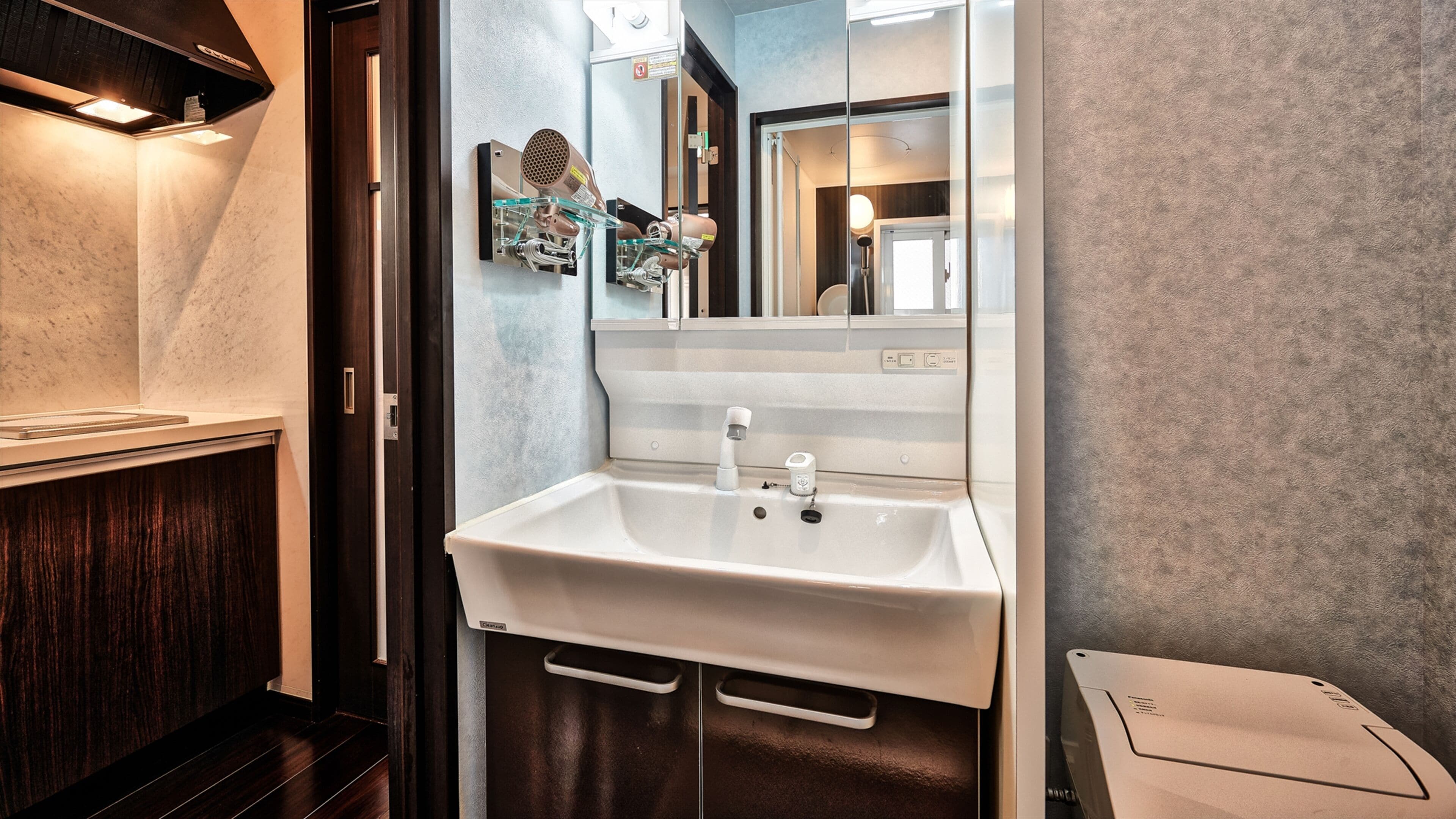 A modern bathroom with a white sink, a glass shower enclosure, and a mirror with a built-in light.