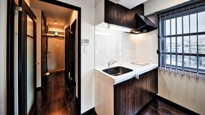 A compact kitchen with a sink, cabinets, and a window with bars. - Terrace Resort Shintoshin (Naha)