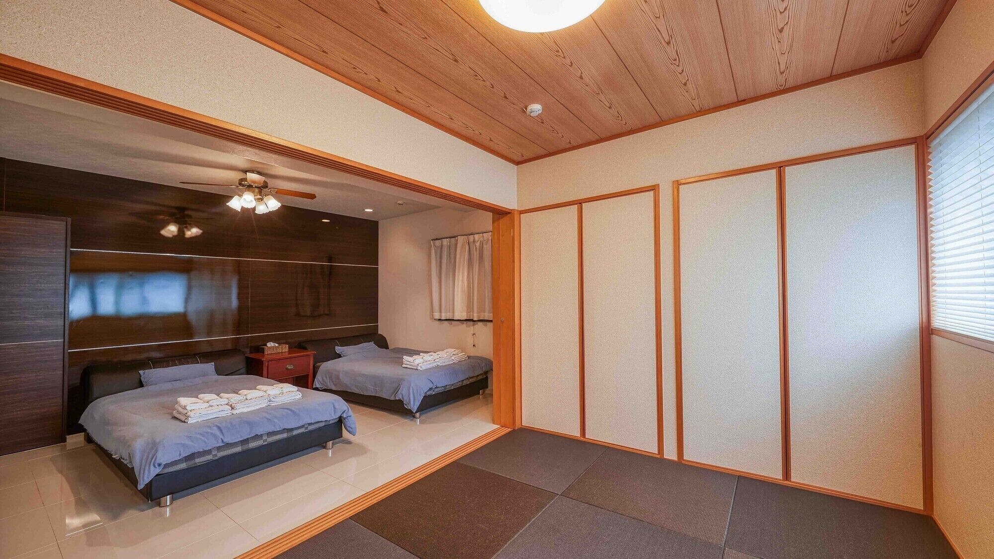 A modern bedroom with two beds, a wooden ceiling, and a sliding shoji screen.
