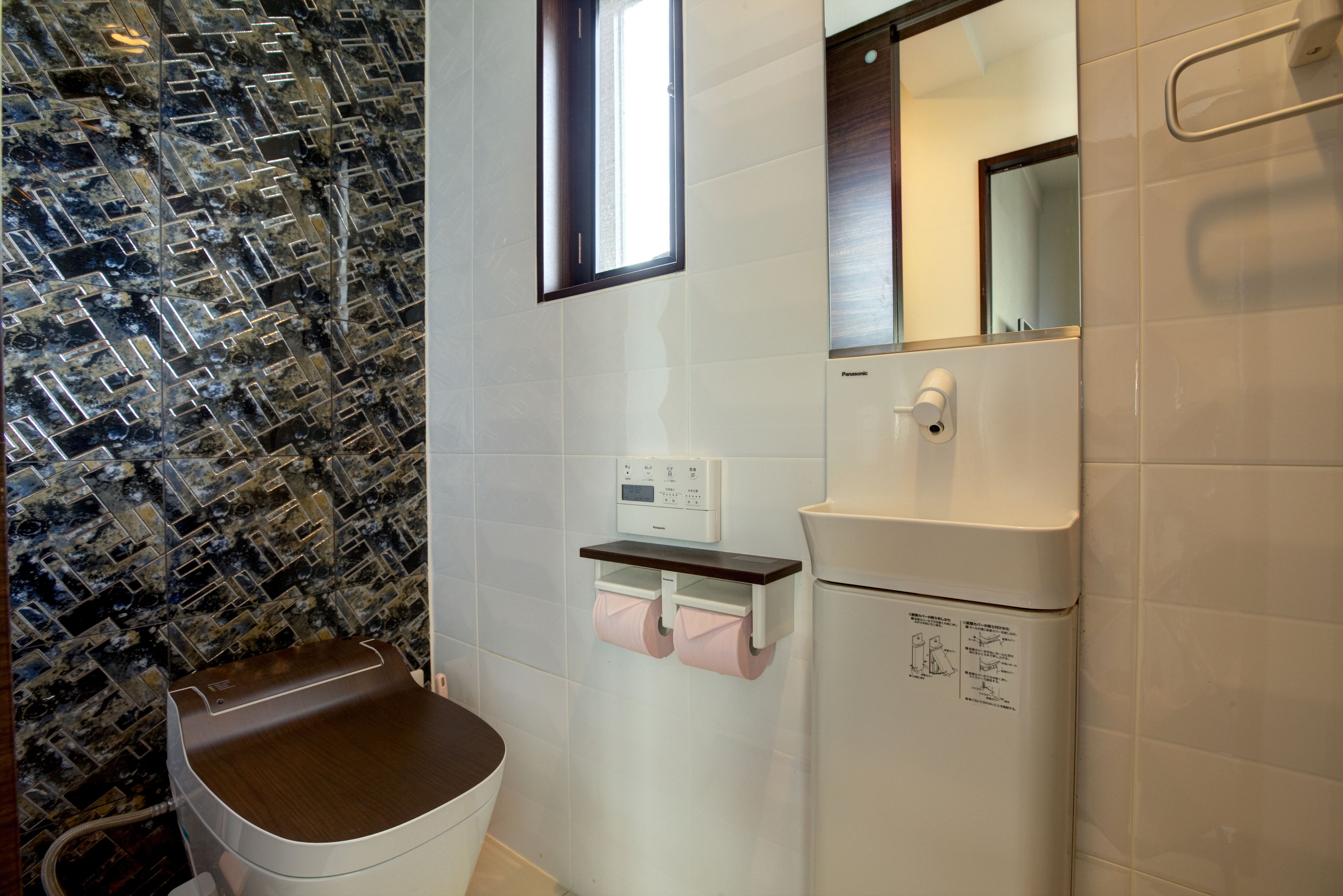 A bathroom with a toilet, a sink, and a mirror.