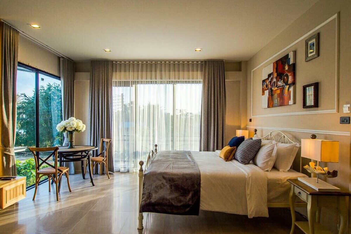 Habitación de hotel con una cama grande, un escritorio y una silla. Tiene una ventana con cortinas y una obra de arte en la pared.