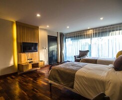 Una habitación de hotel con dos camas, un televisor, un armario de madera y un ventanal con cortinas.