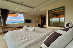 Quarto de hotel com uma cama grande, televisão, janela com vista para a cidade e varanda.