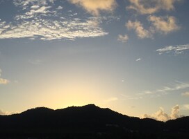 Silueta de una cadena montañosa contra un cielo despejado con algunas nubes.