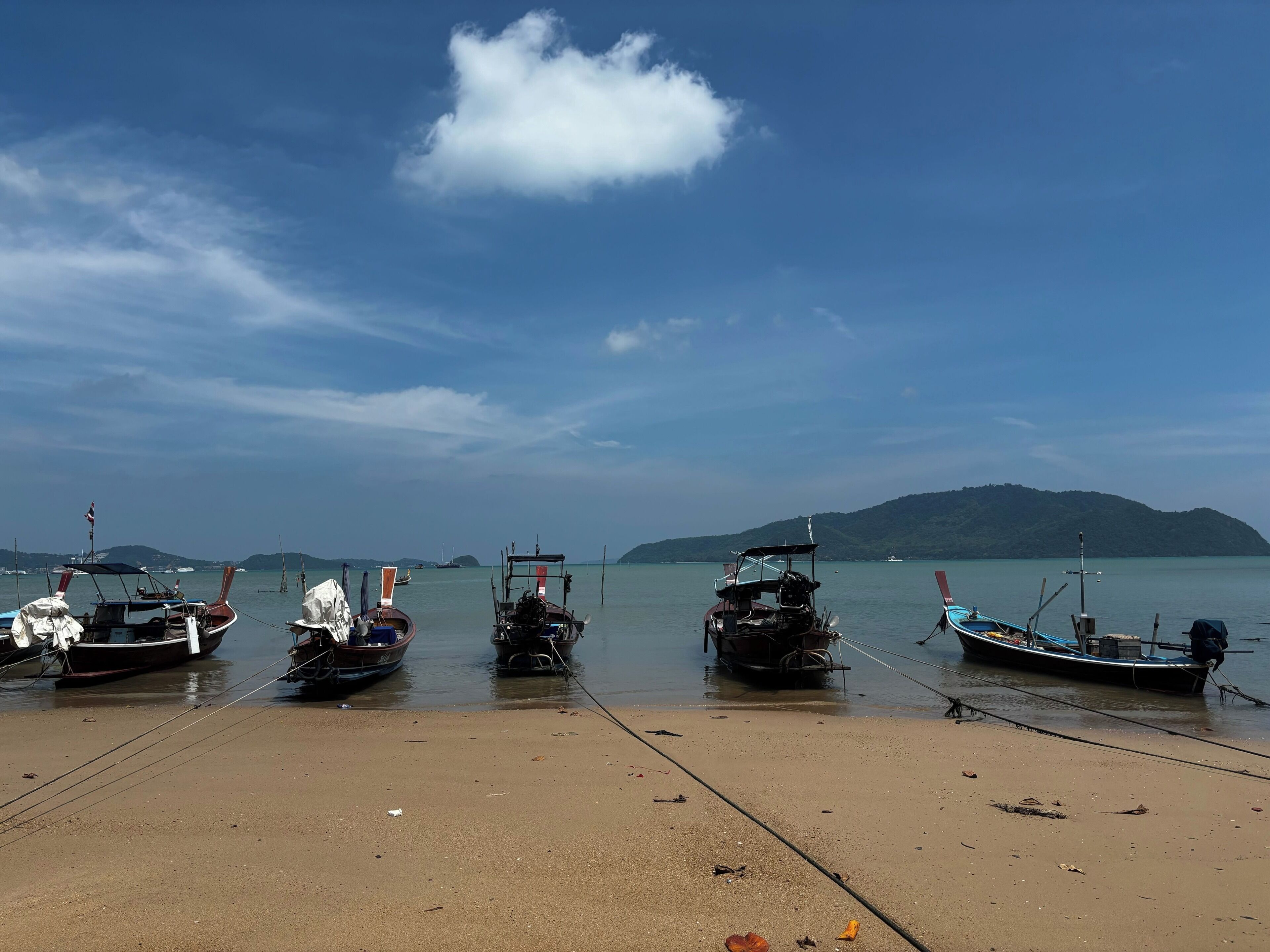 A beach with boats docked, a clear sky, and distant hills.