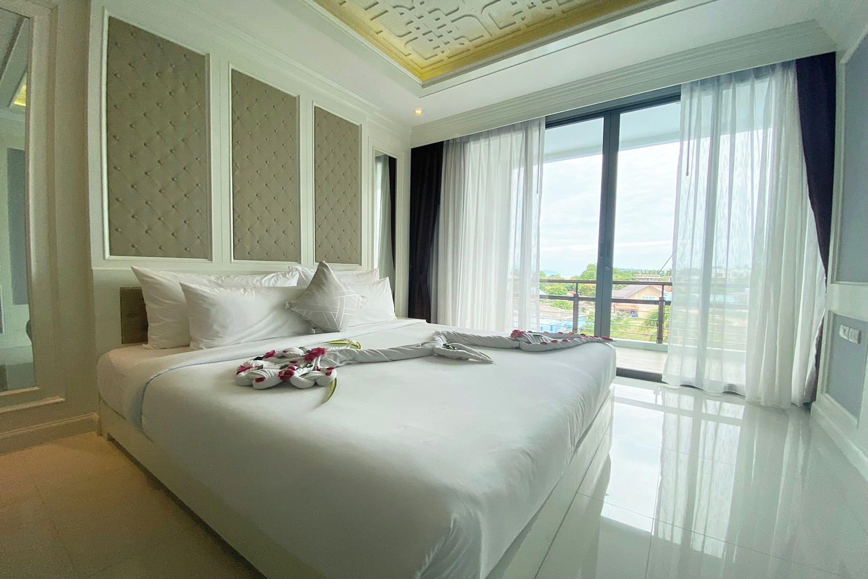 A spacious hotel room with a large bed, a view of the outdoors, and a modern ceiling design.