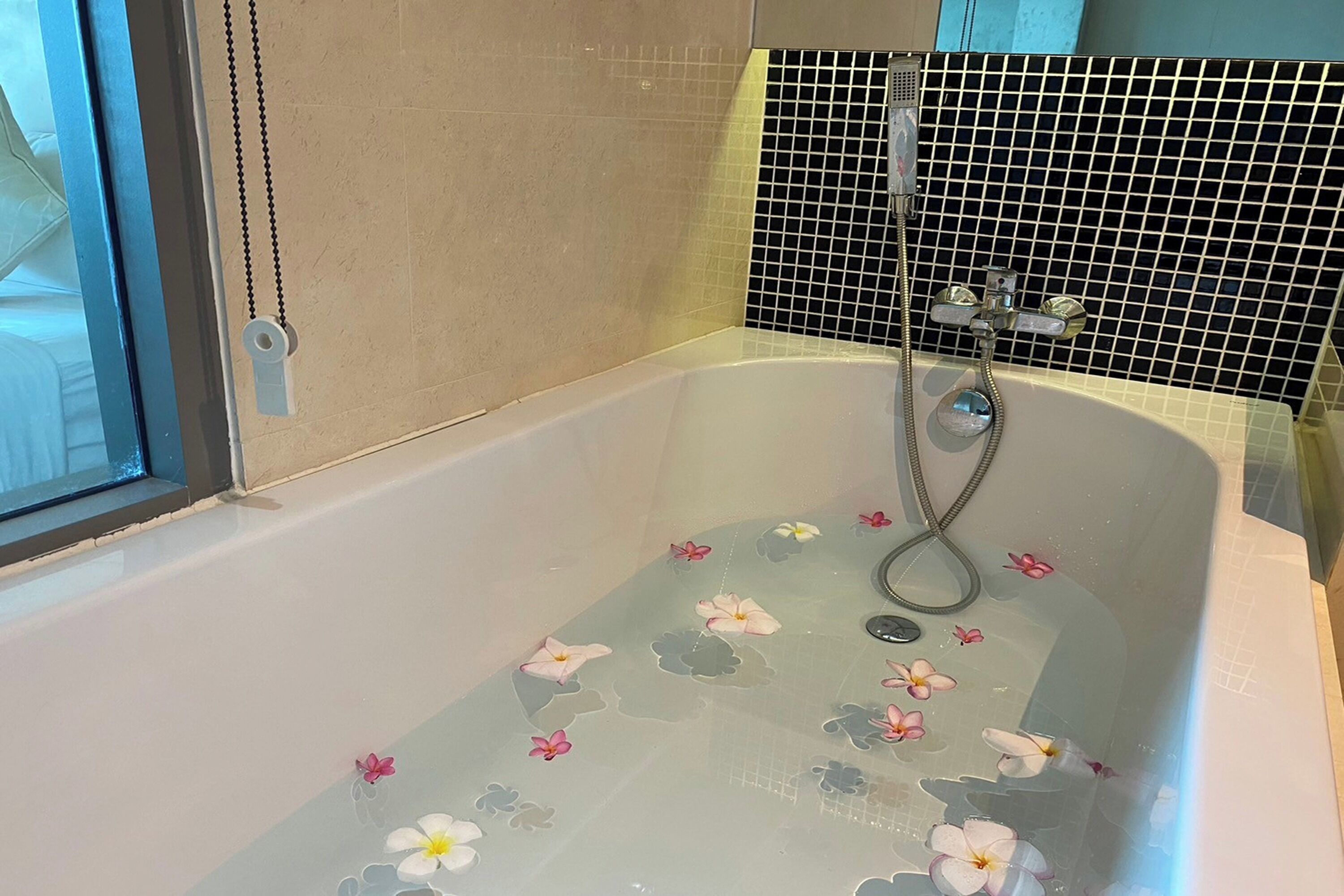 A bathtub with a shower head and a window.