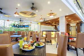 A restaurant with tables set for dining, a sign reading "AQUA RESORT", and a modern interior design. - Aqua Resort Phuket - Near Beach and Chalong Pier (Rawai)