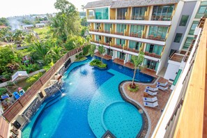A multi-story hotel with a large central pool, outdoor seating areas, and lush greenery surrounding the property. - Aqua Resort Phuket - Near Beach and Chalong Pier (Rawai)