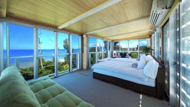 A bedroom with a large bed, a green sofa, and a view of the ocean. - La Casa Panacea Okinawa Resort (Onna)