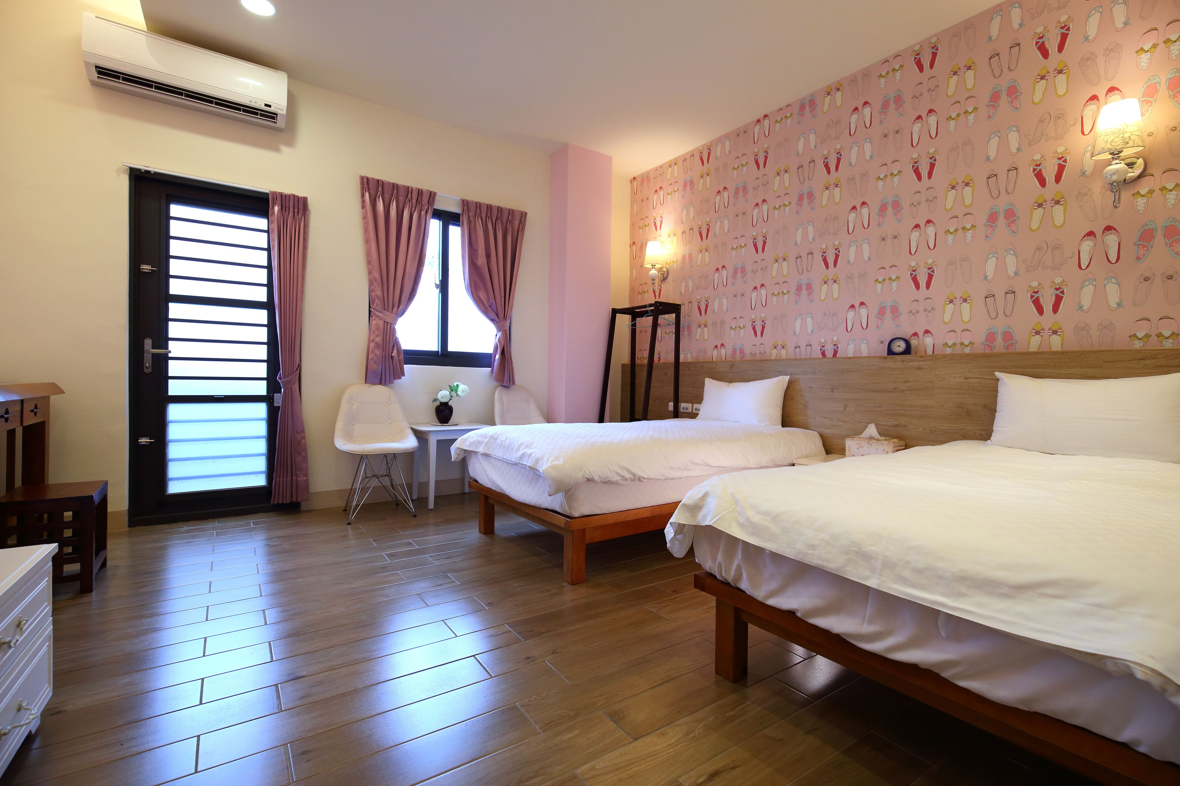 Une chambre d’hôtel avec deux lits, un bureau, une chaise et une fenêtre avec des rideaux.