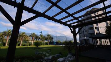 A view through a wooden pergola with a clear sky and palm trees.