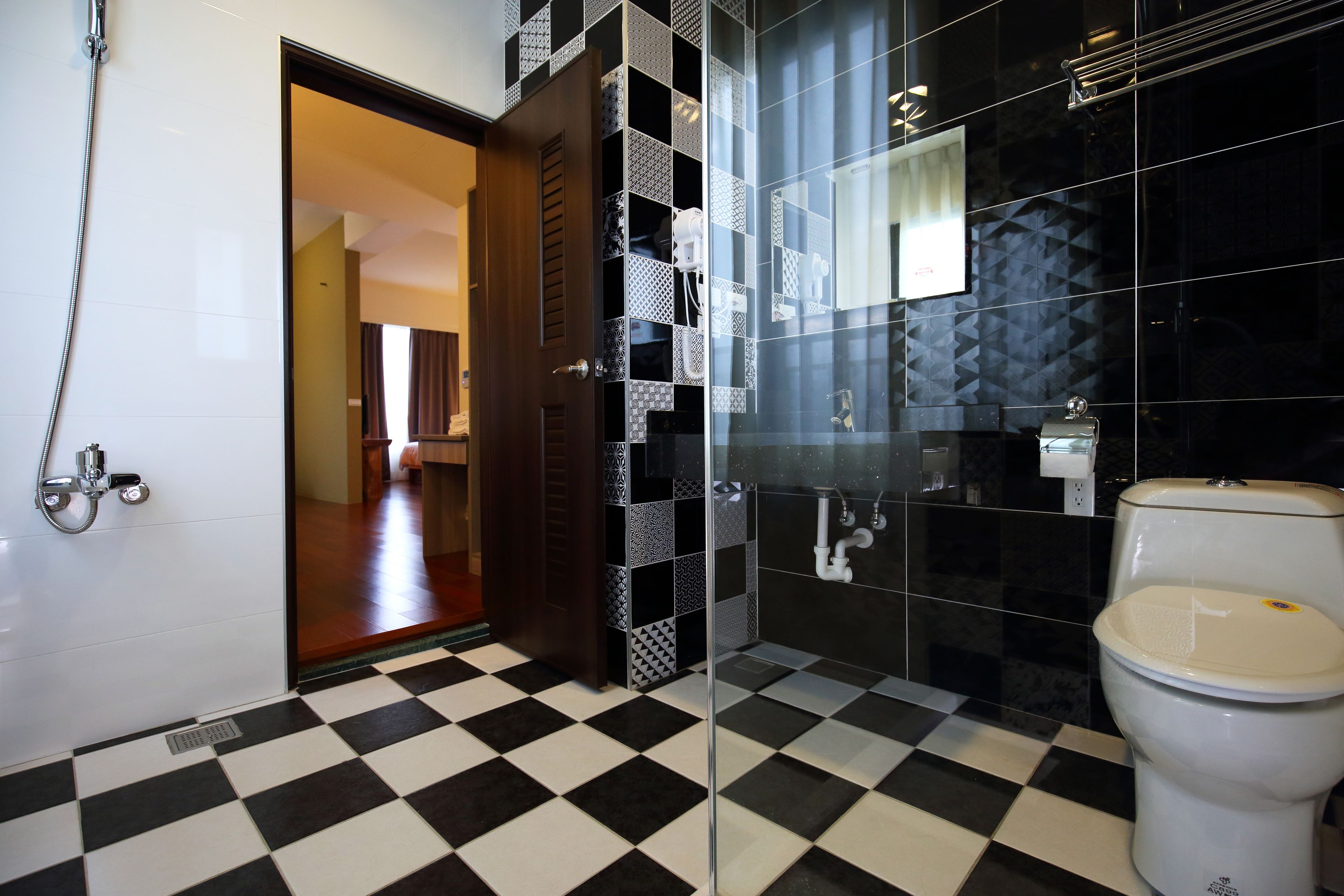A bathroom with a checkered floor, a toilet, a shower, and a glass partition.