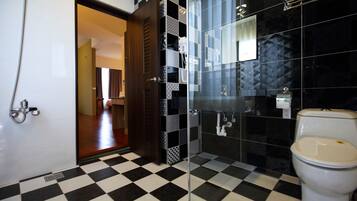 Un baño con piso a cuadros, inodoro, ducha y mampara de vidrio.