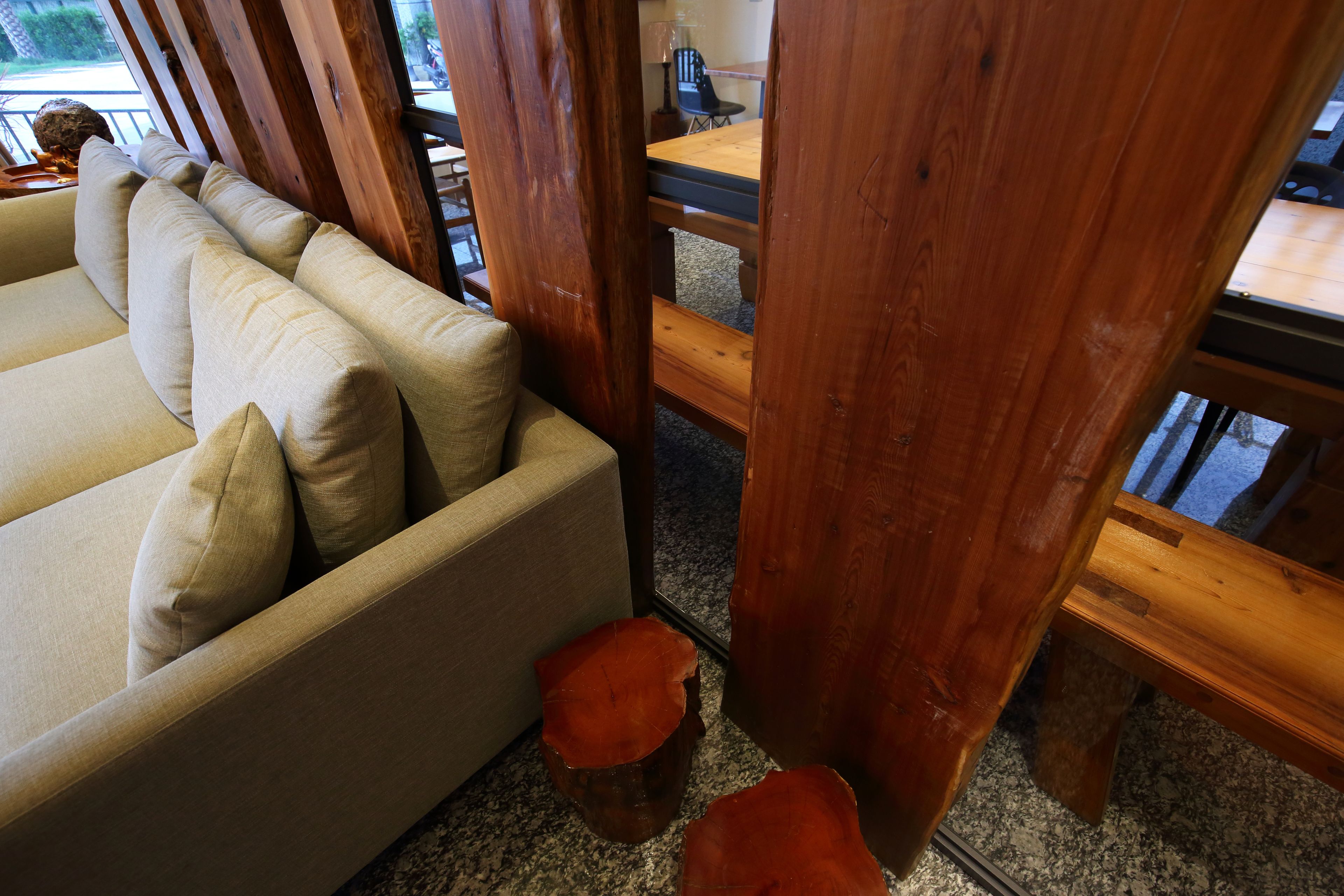 Ein Holzespeisesaal mit Stühlen, ein beiges Sofa mit Kissen und ein Steinfußboden.