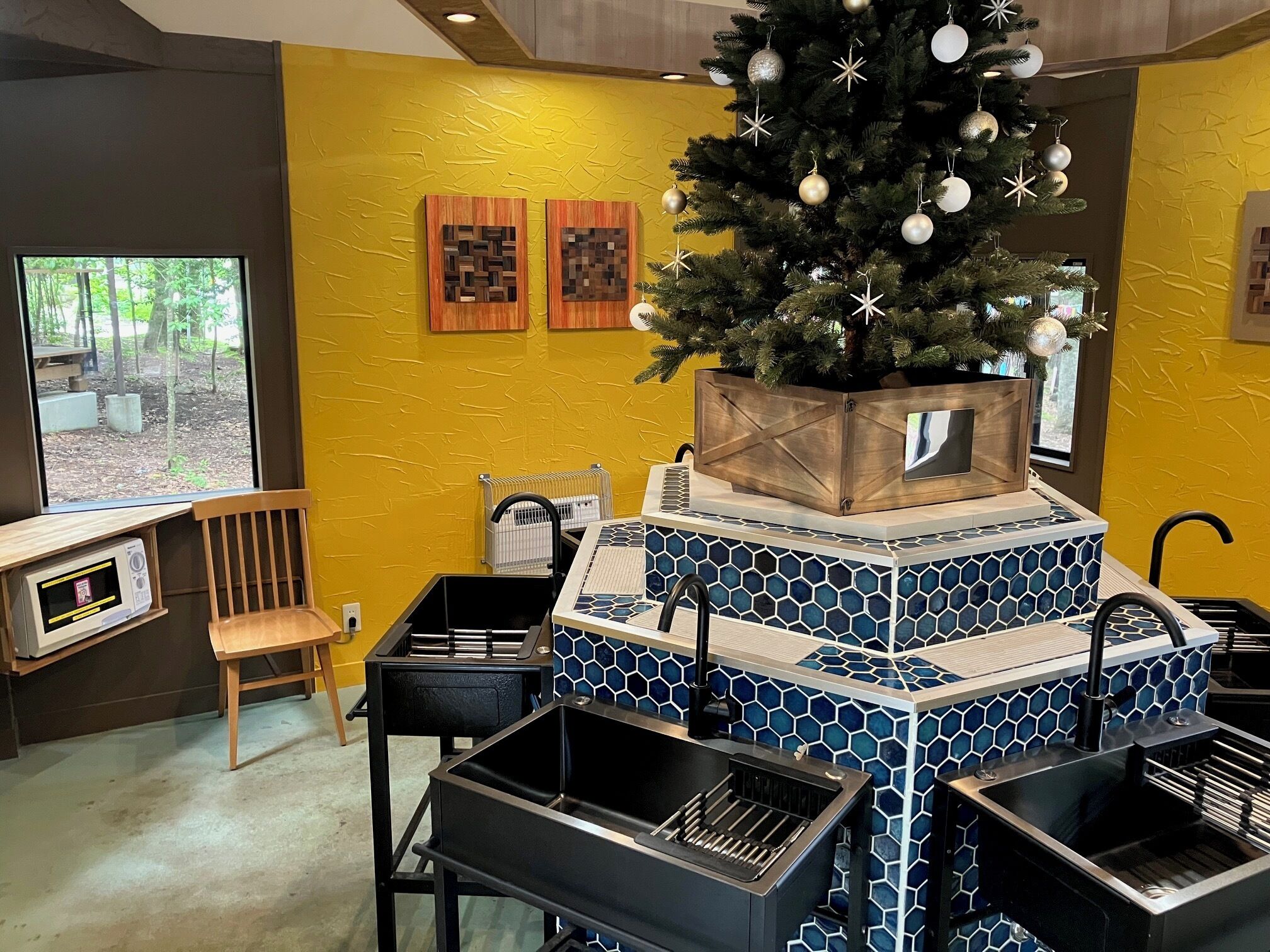 A kitchen area with a Christmas tree, a microwave, and a coffee machine.