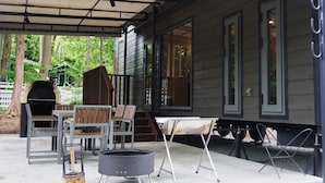 A covered patio with outdoor furniture, a grill, and a fire pit.