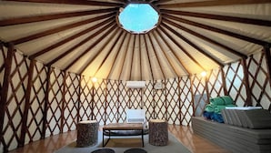 A yurt interior with a central seating area, a table, and a couch. - PICA FUJIYOSHIDA - Campsite (Fujiyoshida)