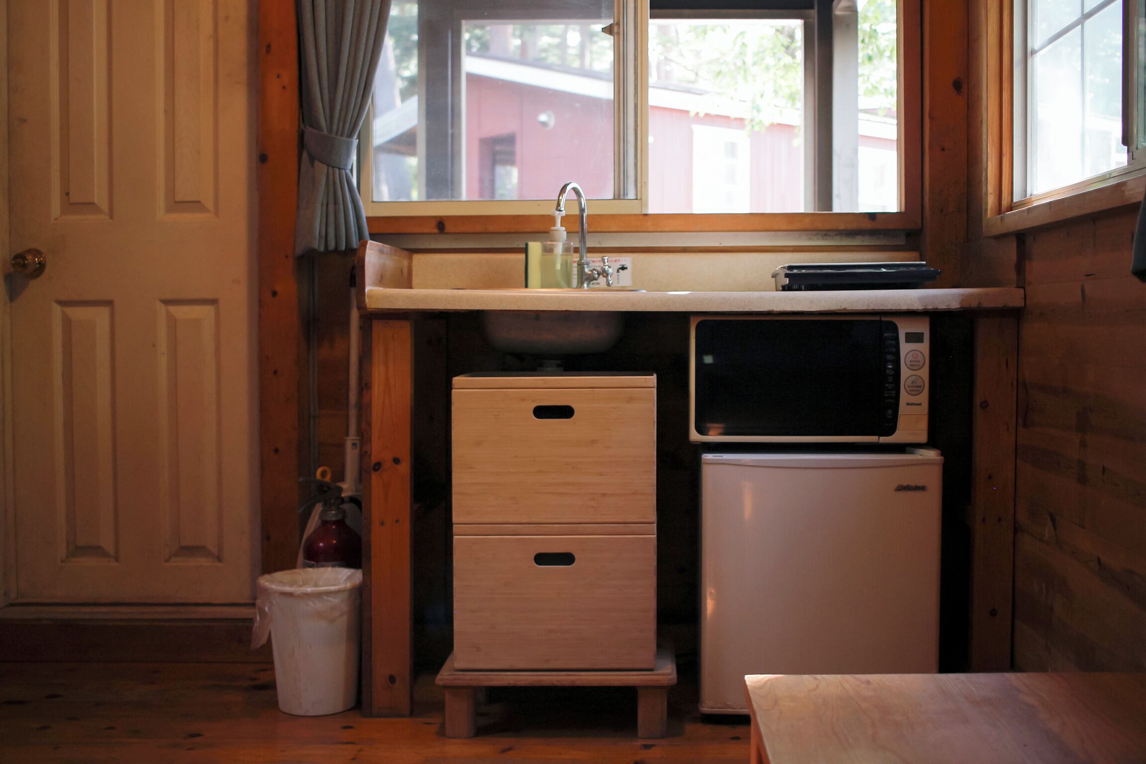 A compact kitchen with a sink, microwave, and a small refrigerator.
