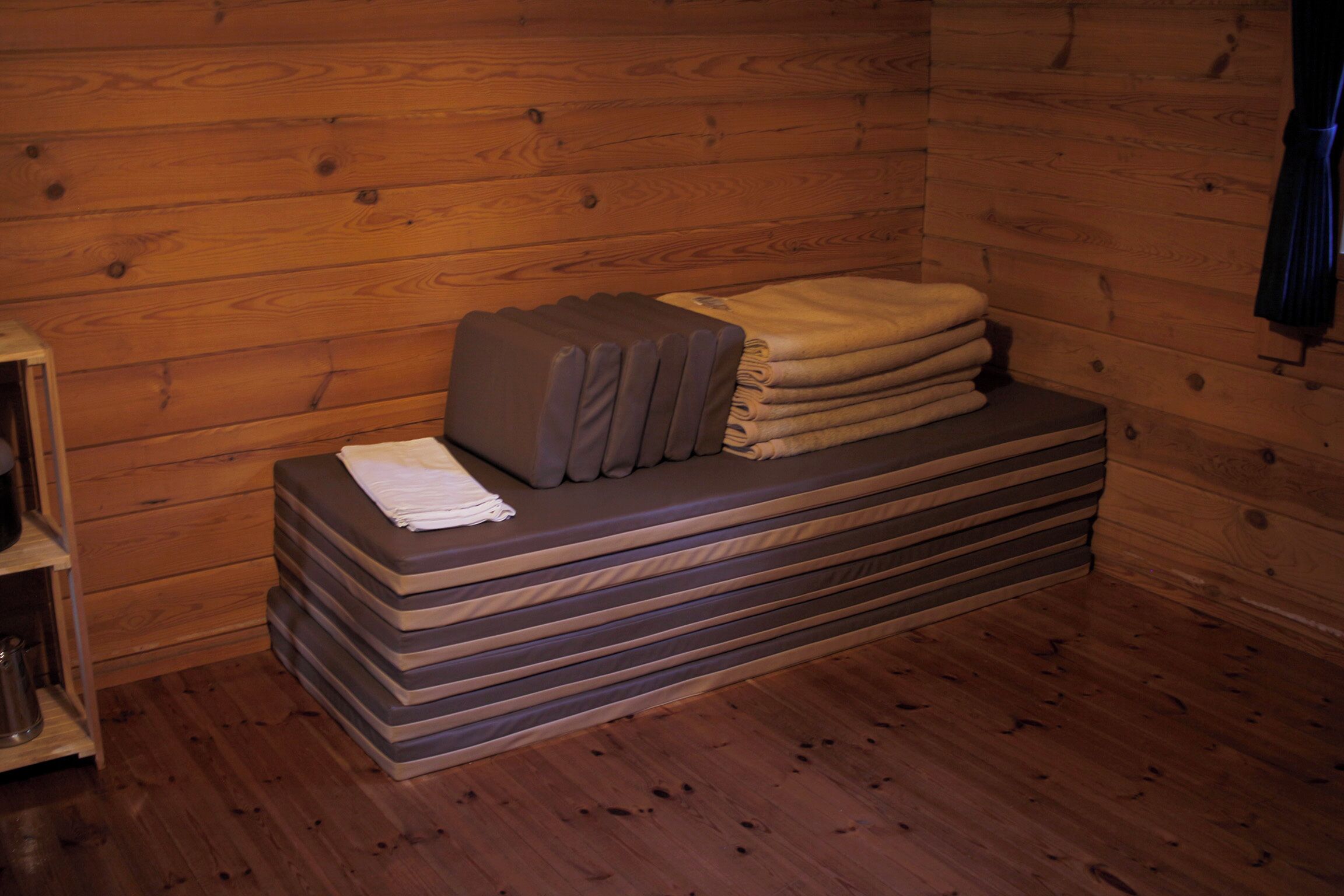 A wooden cabin interior with a bench, towels, and a shelf.