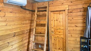 A wooden interior with a ladder, a door, and an air conditioning unit.