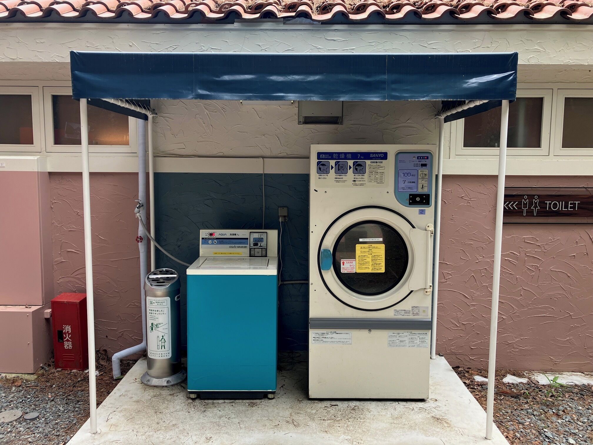 A laundry facility with a washing machine and dryer, a water dispenser, and a fire extinguisher.