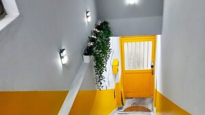 A staircase with a yellow and white color scheme, leading to a door with a window. - Hause Itaewon - Hostel (Seoul)