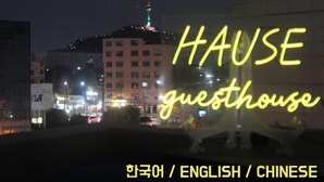 A night view of a building with illuminated signage reading "HAUSE guesthouse" in multiple languages. - Hause Itaewon - Hostel (Seoul)