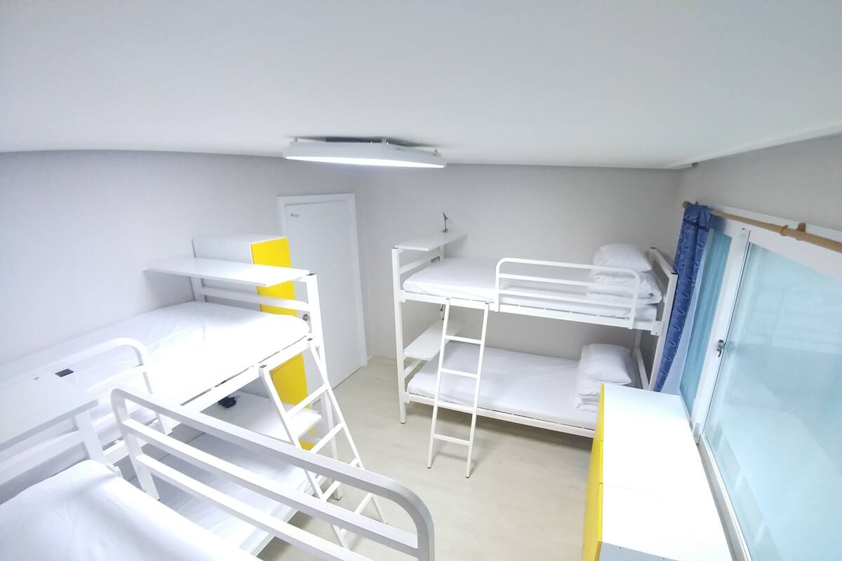 A bunk bed room with a desk, a chair, and a window with curtains.
