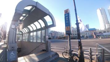 A covered bus stop with a bicycle parked nearby, a clear sky, and buildings in the background.