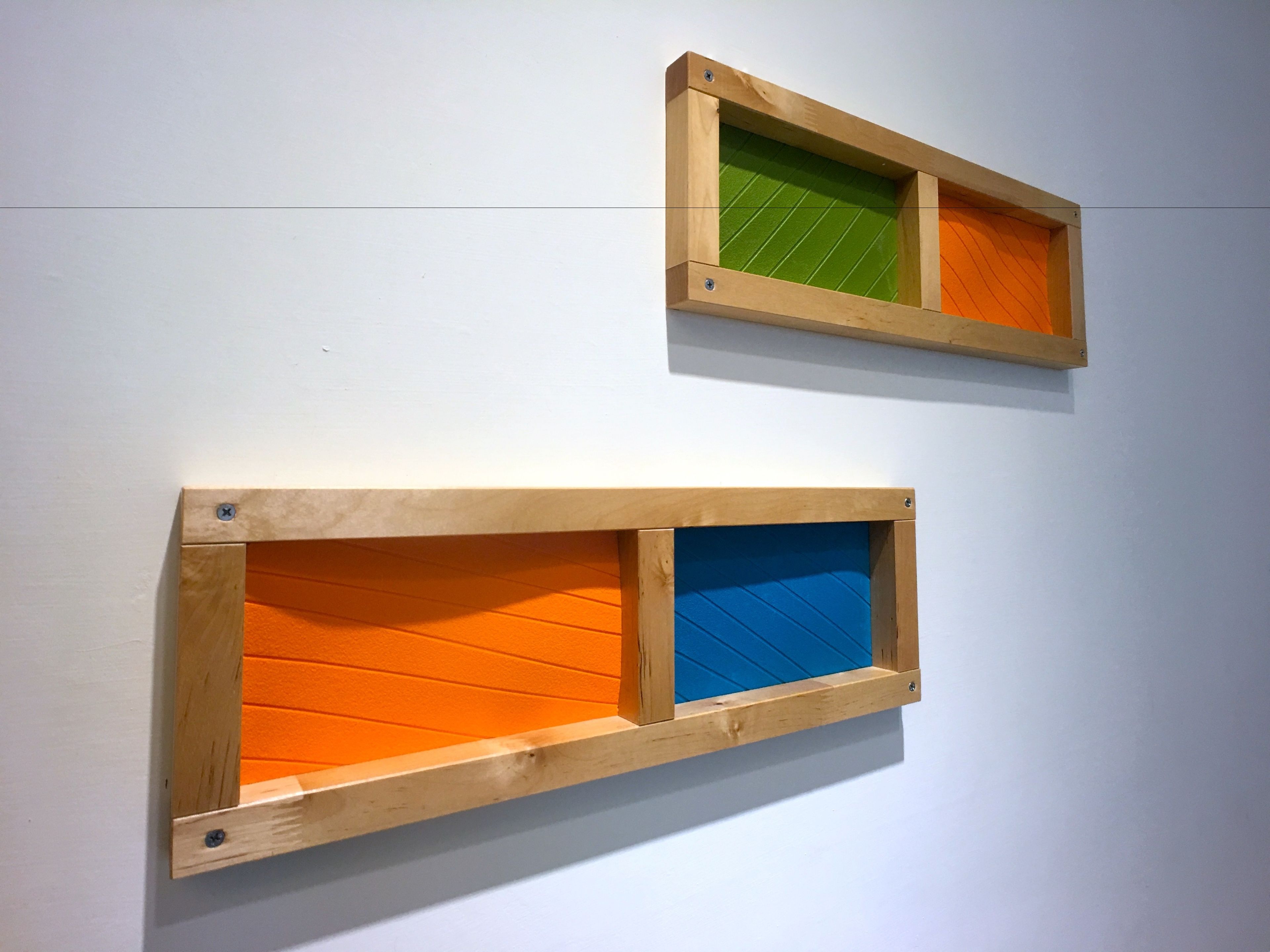 Two wooden frames with colored panels on a white wall.