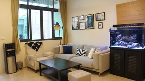 A living room with a sofa, coffee table, ottoman, and a fish tank. - Dio Inn (Hengchun)