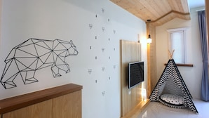 A modern interior with a geometric bear wall art, a mounted TV, and a wooden ceiling. - Dio Inn (Hengchun)