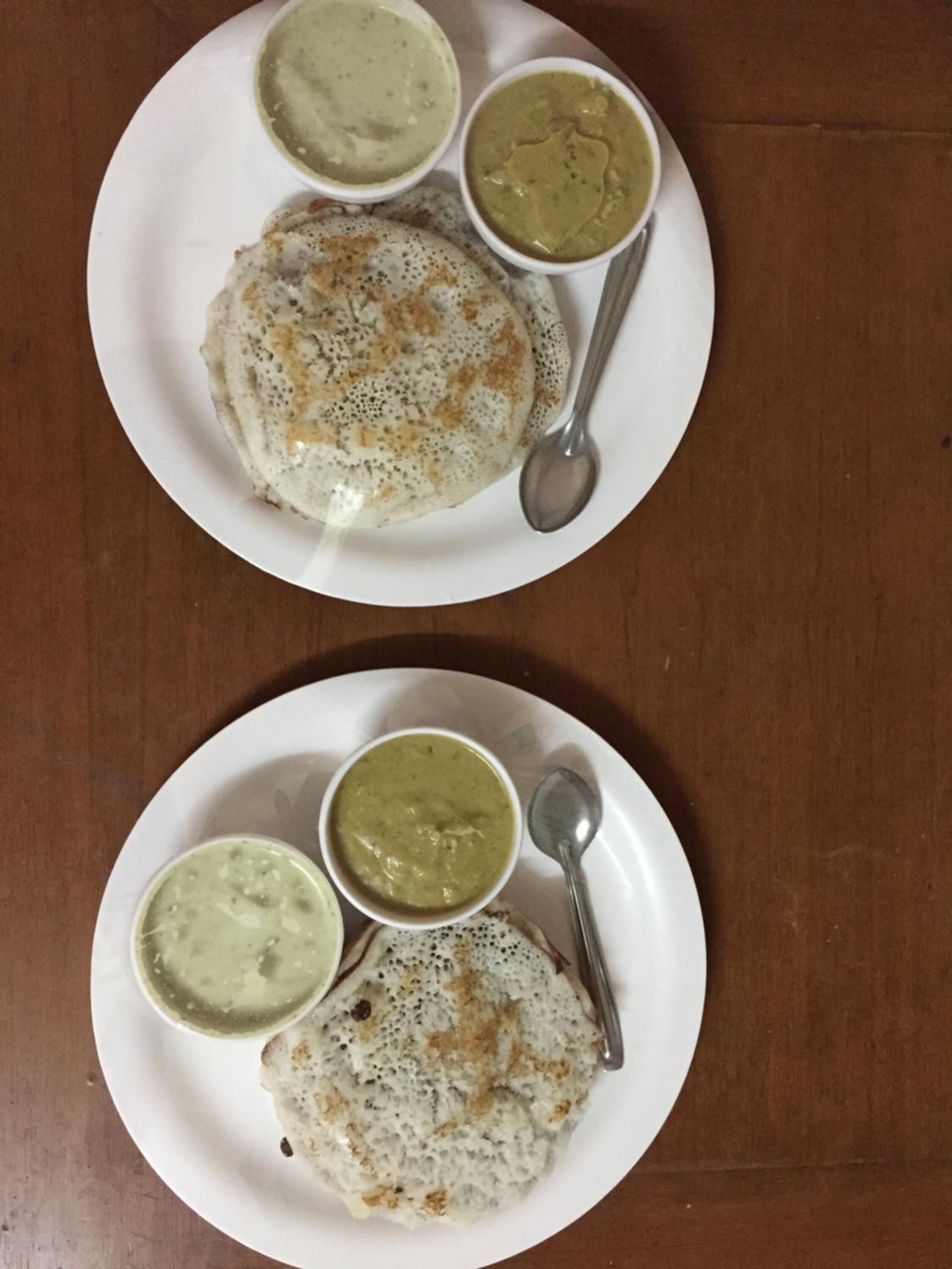Two plates with a dosa and two types of chutney.