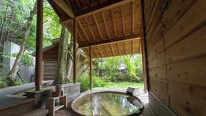 Uma cabana de madeira com hidromassagem, degraus de madeira e um terraço coberto.