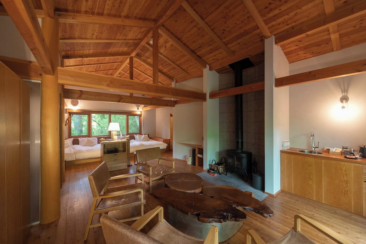 Un vaste espace de vie doté d’un plafond en bois, d’une cheminée et d’un coin cuisine avec des meubles en bois.