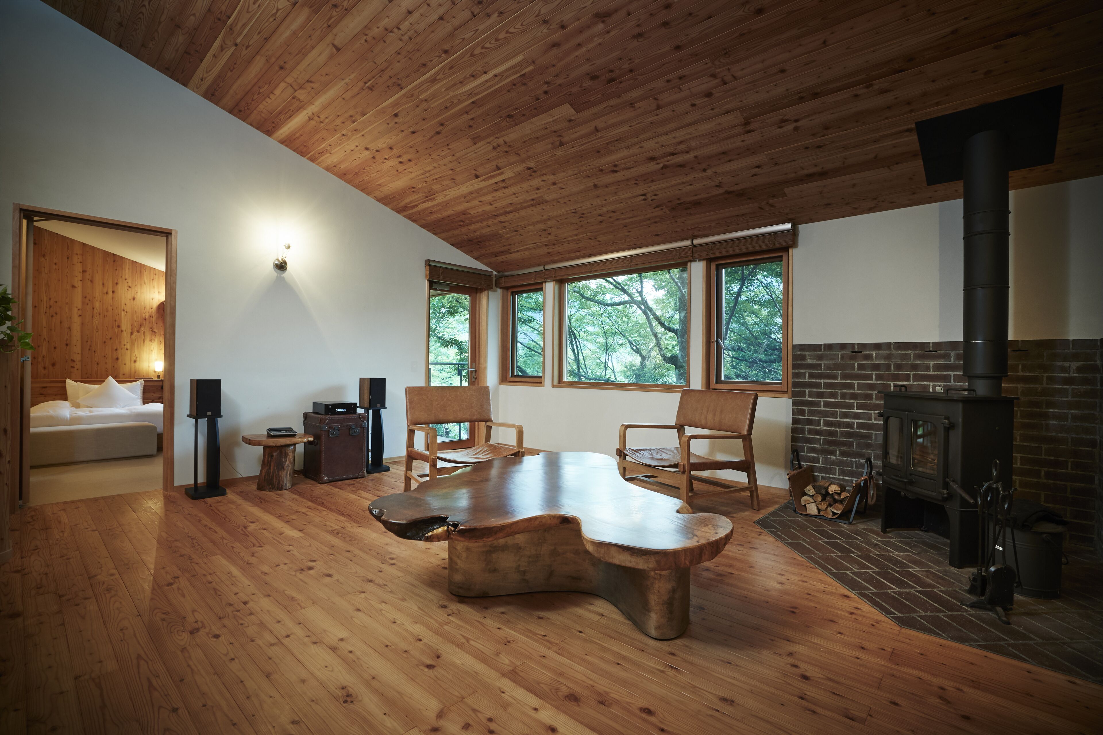 Un interior moderno con techo de madera, chimenea y ventanas grandes.
