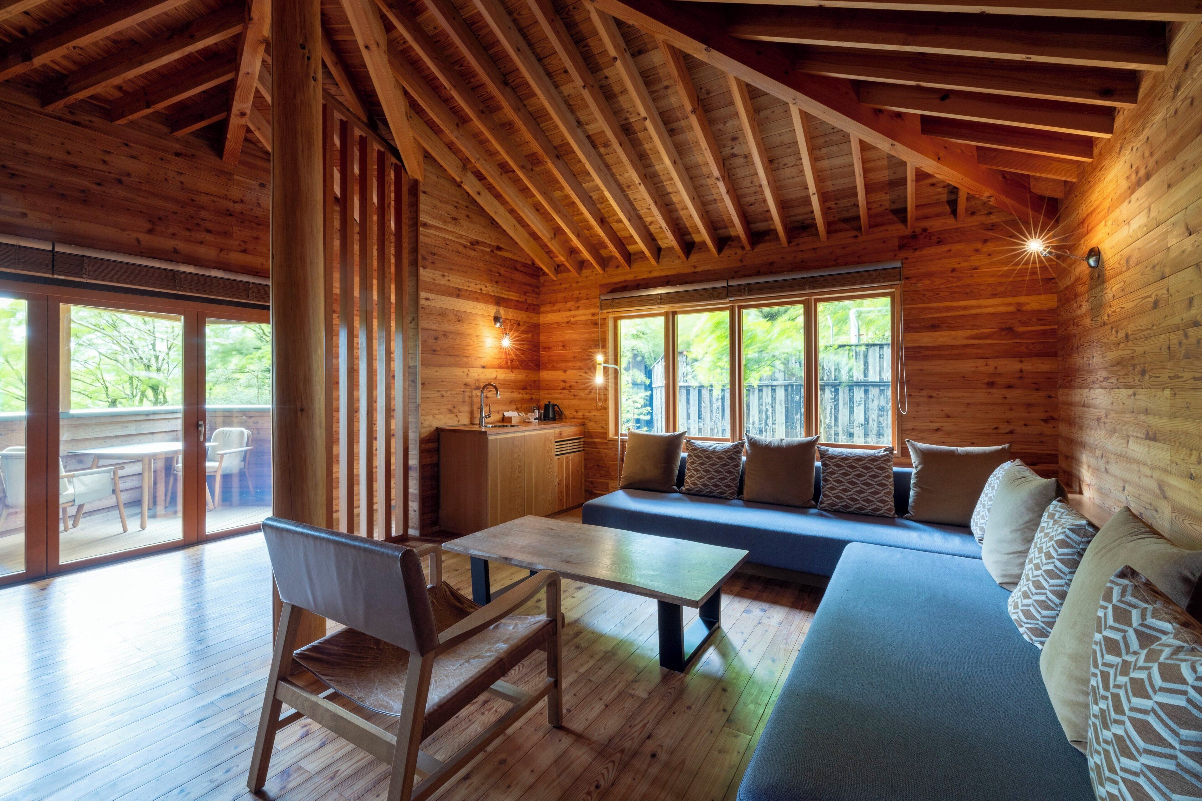 A wooden cabin interior with a dining area, a sofa, and a kitchen.