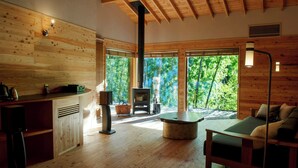 A spacious room with a wooden interior, a large window, a sofa, a table, and a fireplace.