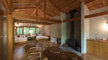 A spacious living area with a high ceiling, wooden beams, a fireplace, and a dining area with a sink.
